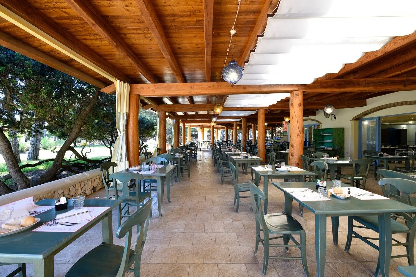 Ristorante all'aperto con tavoli apparecchiati sotto un porticato in legno
