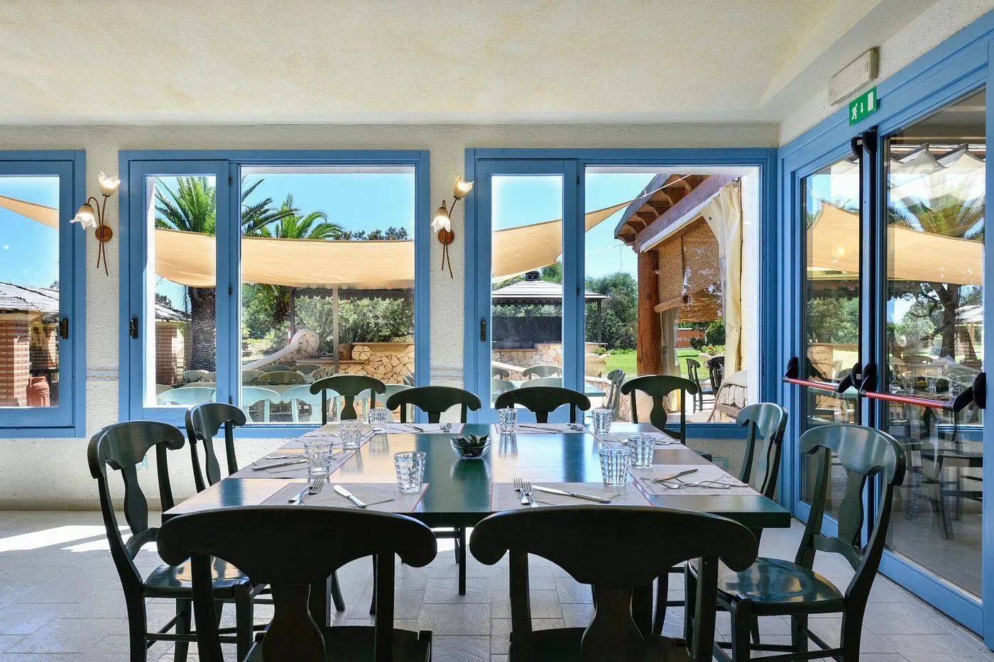 Sala ristorante interna con tavoli apparecchiati e ampie vetrate sul giardino