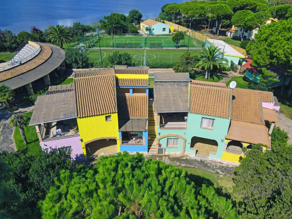 Vista aerea delle colorate strutture del resort con campo da calcio e laguna