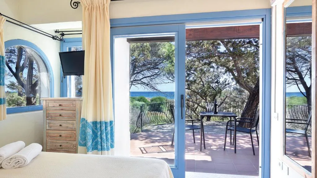 Camera con porta finestra sul terrazzo e vista mare tra i pini