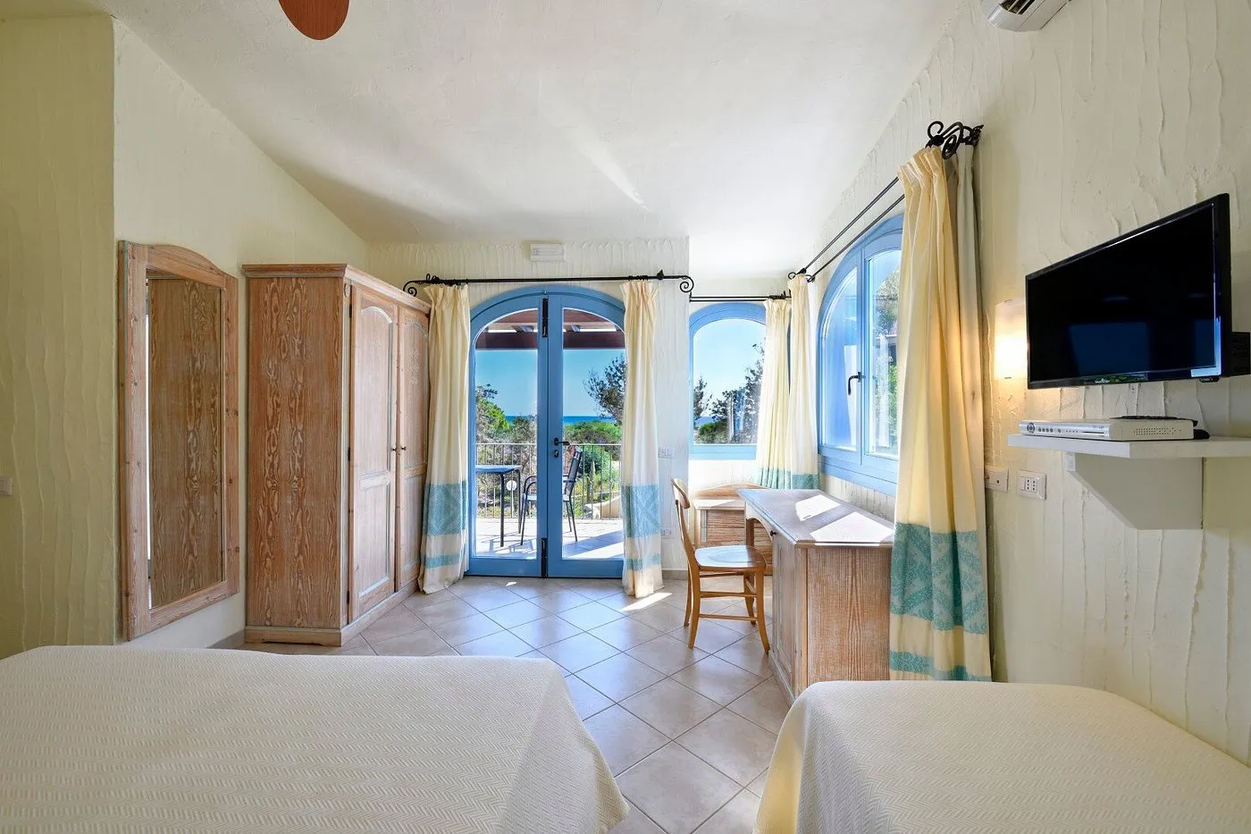 Camera con letti, armadio in legno e accesso al terrazzo con vista mare
