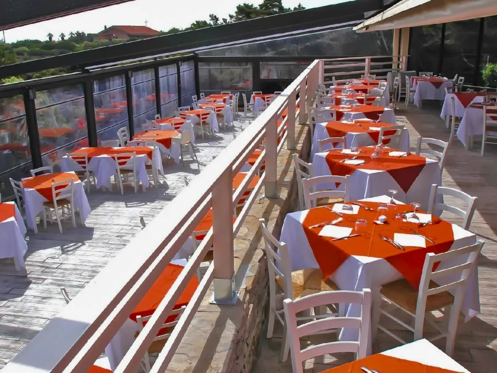 Terrazza ristorante con tavoli apparecchiati con tovaglie arancioni e bianche