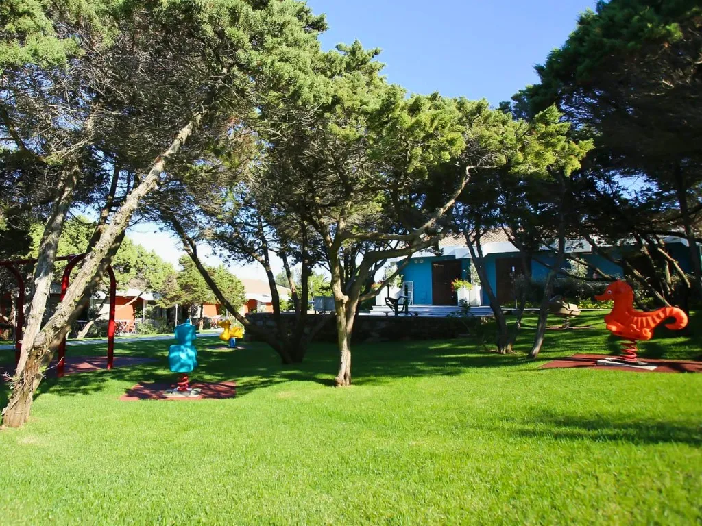 Area giochi per bambini nel giardino con prato verde e alberi