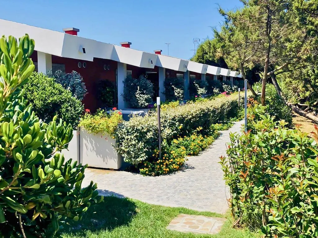 Vialetto del resort tra siepi fiorite e edifici con tetto bianco