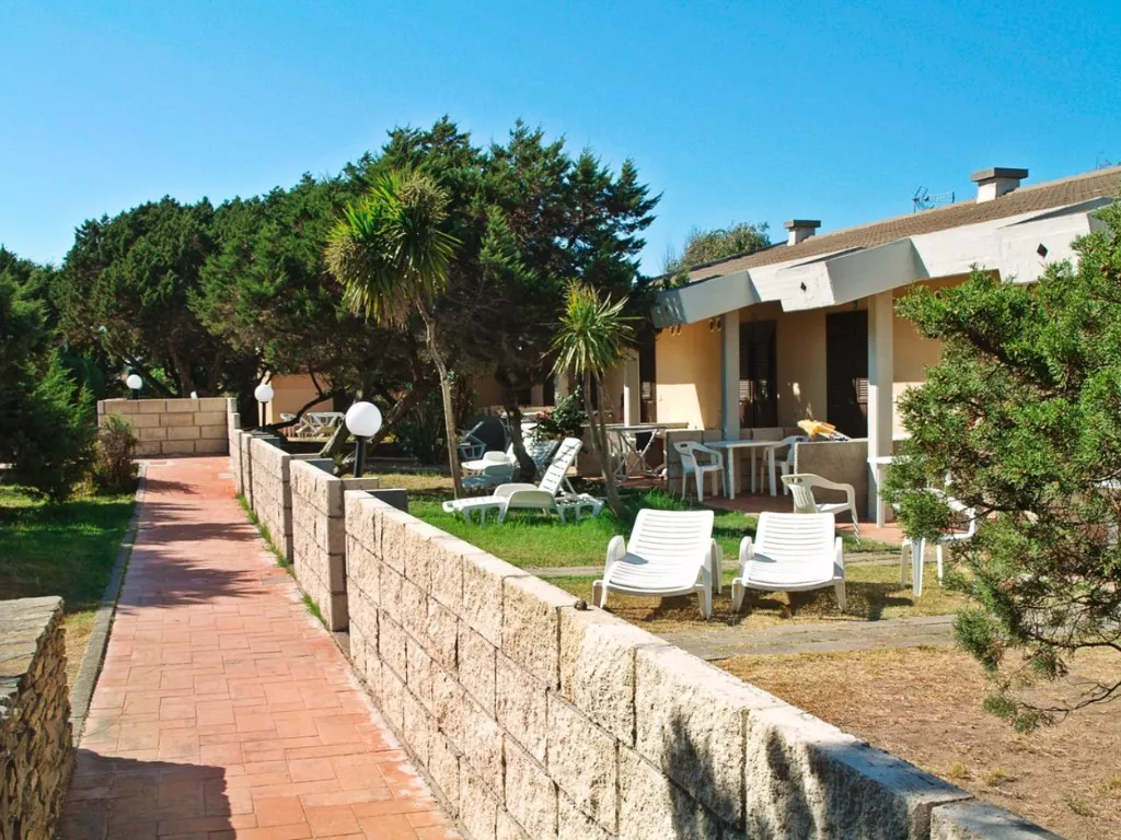 Esterno degli alloggi con veranda, lettini bianchi e giardino privato