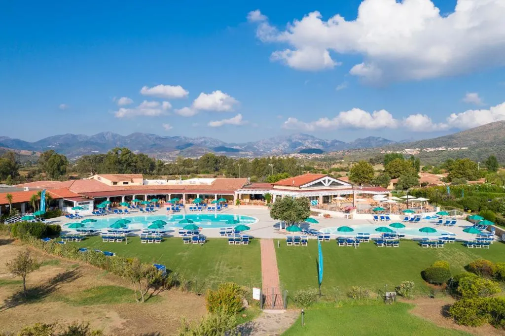 Veduta panoramica del resort con piscina, lettini e montagne sullo sfondo
