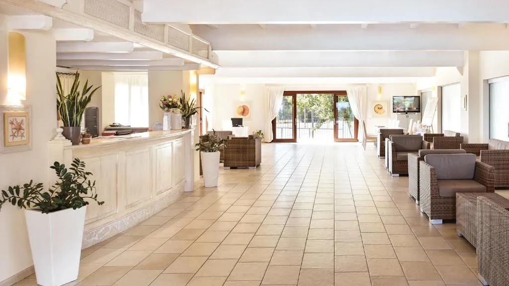 Hall della reception con bancone bianco, poltrone in rattan e piante decorative