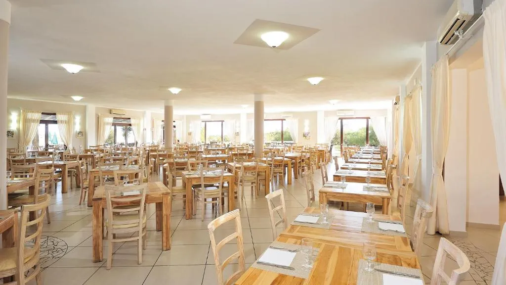Sala ristorante interna luminosa con tavoli e sedie in legno apparecchiati