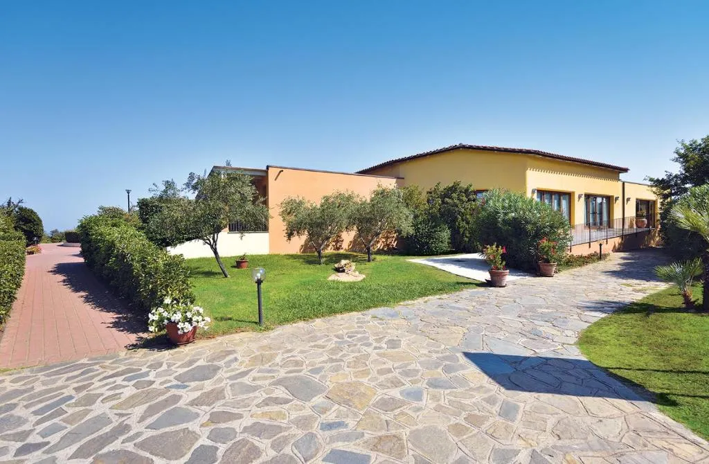 Edificio giallo del resort con vialetto in pietra e giardino curato