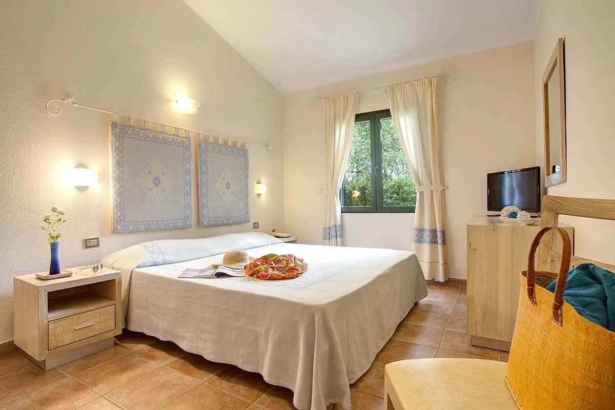 Camera matrimoniale con arredi in legno, decorazioni sarde e TV