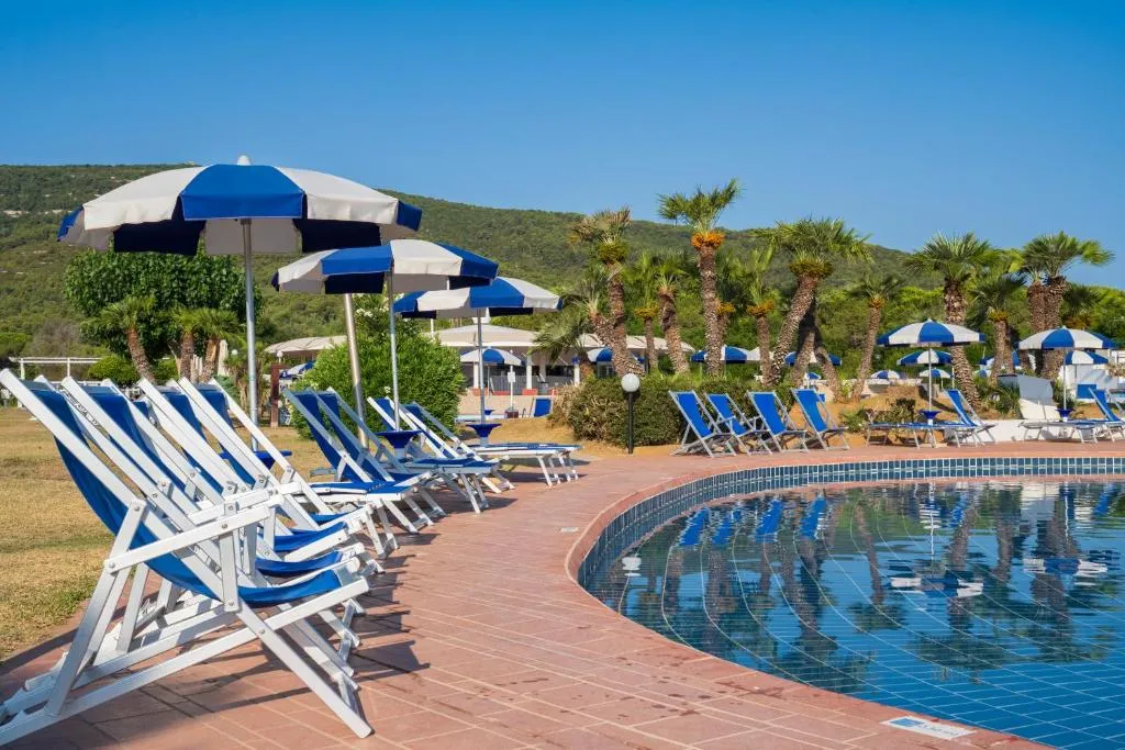 Lettini e ombrelloni blu e bianchi a bordo piscina con colline sullo sfondo