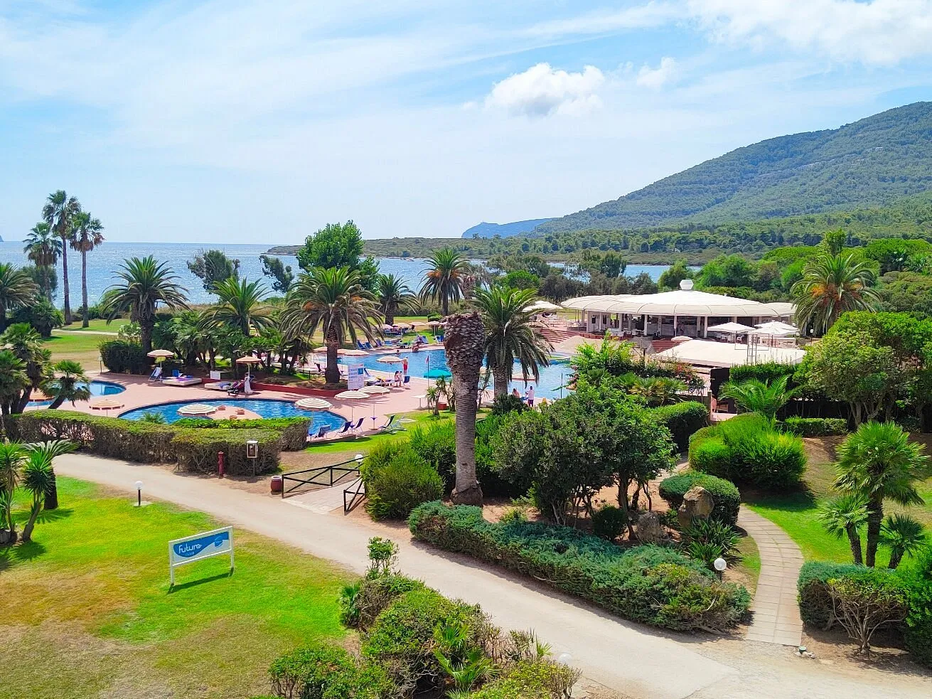 Vista del resort con piscine, palme e bar all'aperto vicino al mare