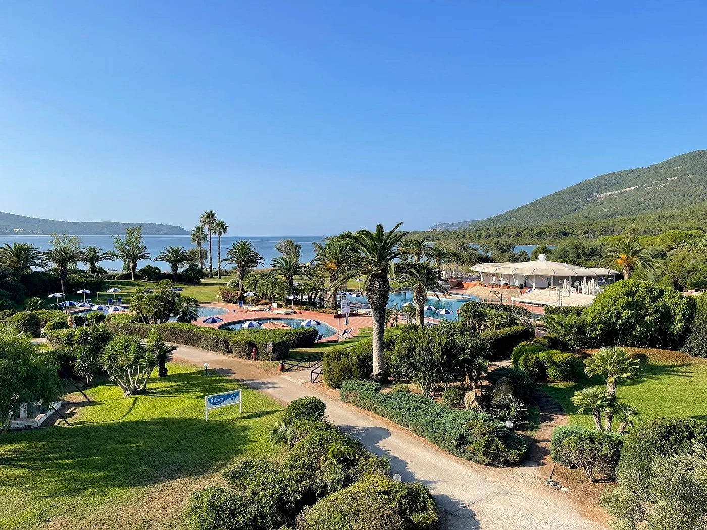 Panorama del resort con piscine, palme e mare al mattino