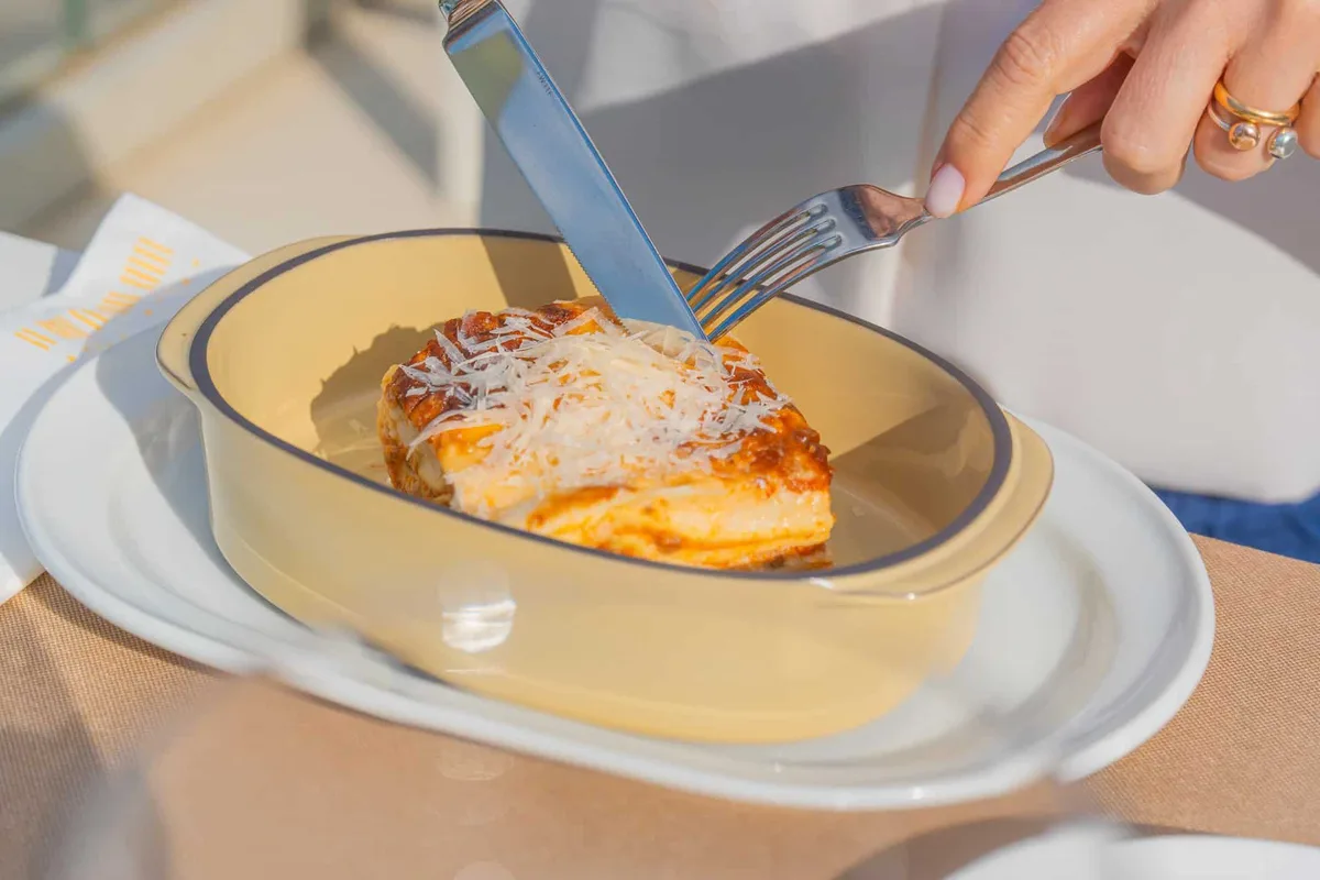 Lasagna gratinata servita in pirofila con parmigiano