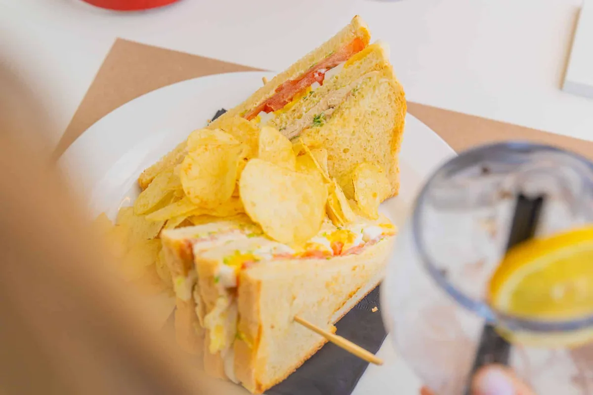 Club sandwich con patatine servito su piatto bianco