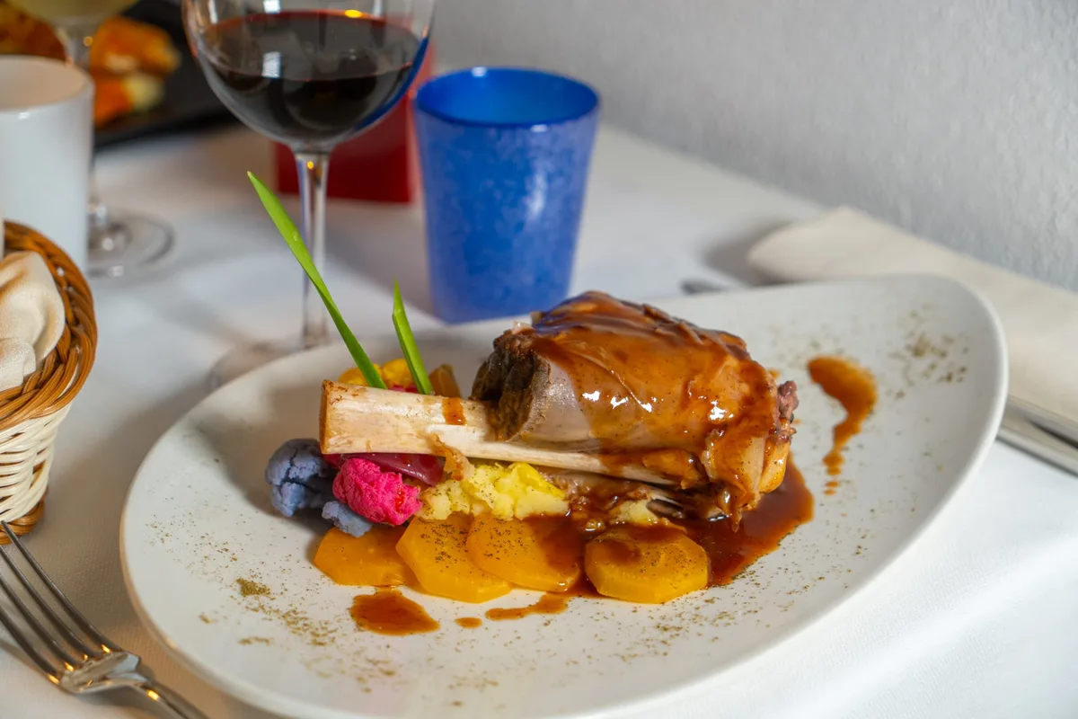 Stinco di maiale glassato con purè e verdure e vino rosso