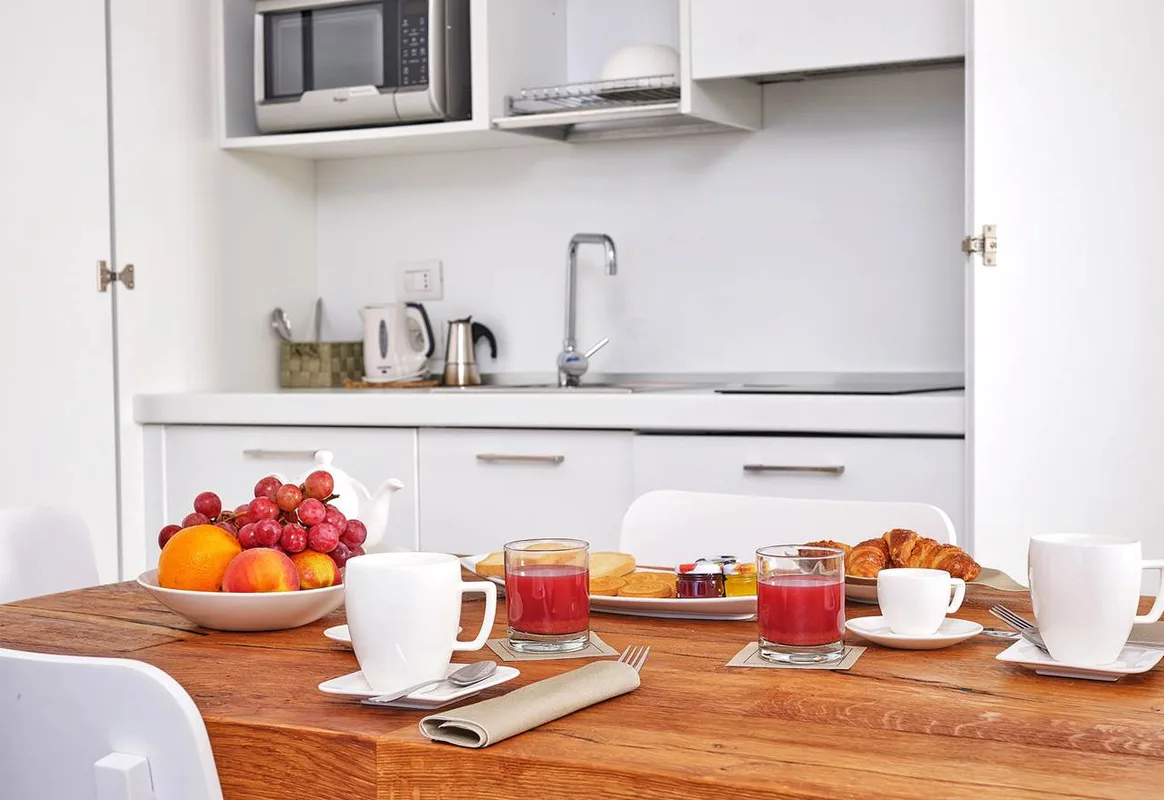 Colazione servita su tavolo in legno con angolo cottura sullo sfondo