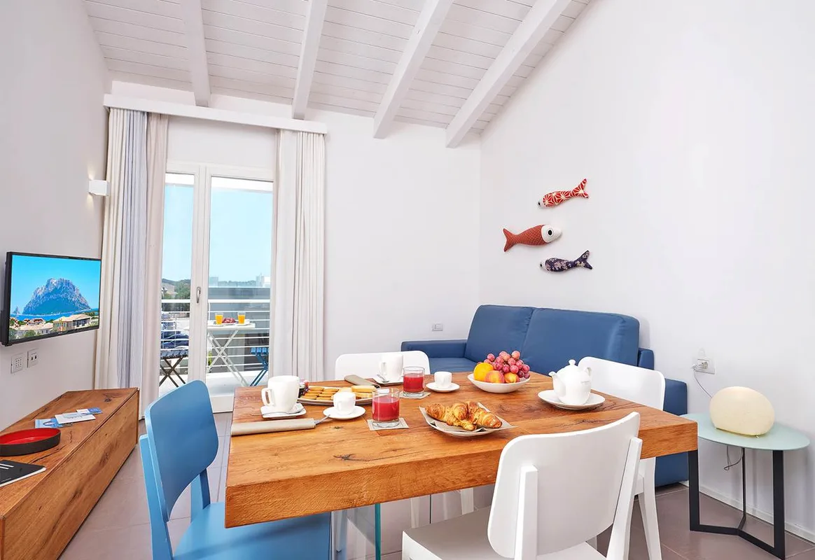 Zona pranzo con colazione, divano blu e vista sul balcone