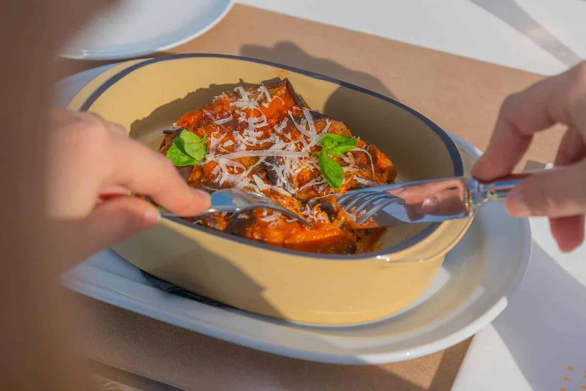 Parmigiana di melanzane con basilico servita in pirofila