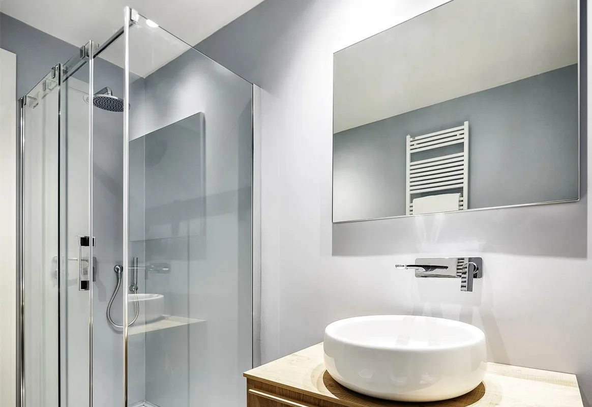 Bagno moderno con box doccia in vetro, lavabo tondo e grande specchio