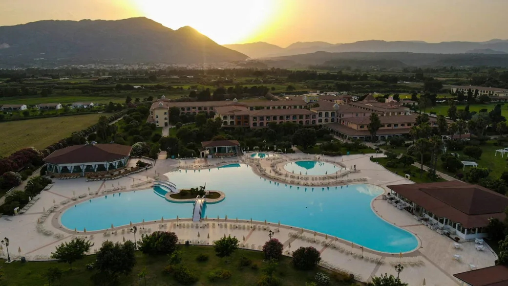Resort con grande piscina al tramonto e montagne sullo sfondo