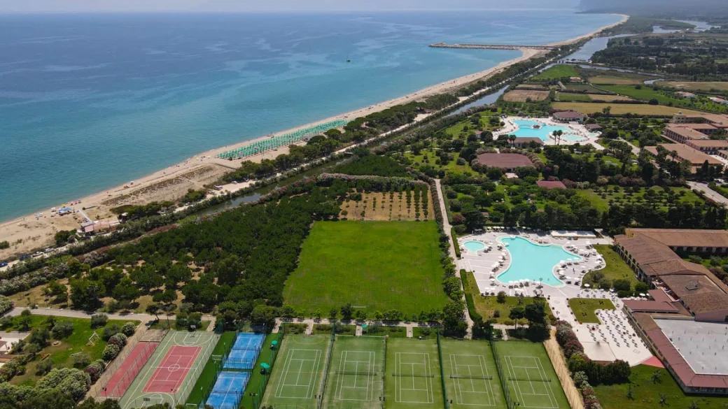 Panoramica aerea del resort con piscine, campi sportivi e spiaggia