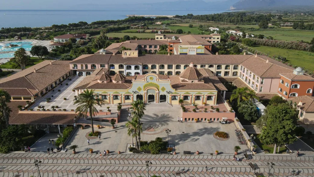 Facciata principale del resort in stile mediterraneo con piazzale e palme