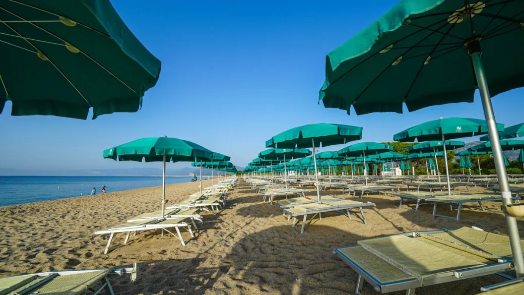 Ombrelloni verdi e lettini sulla spiaggia sabbiosa