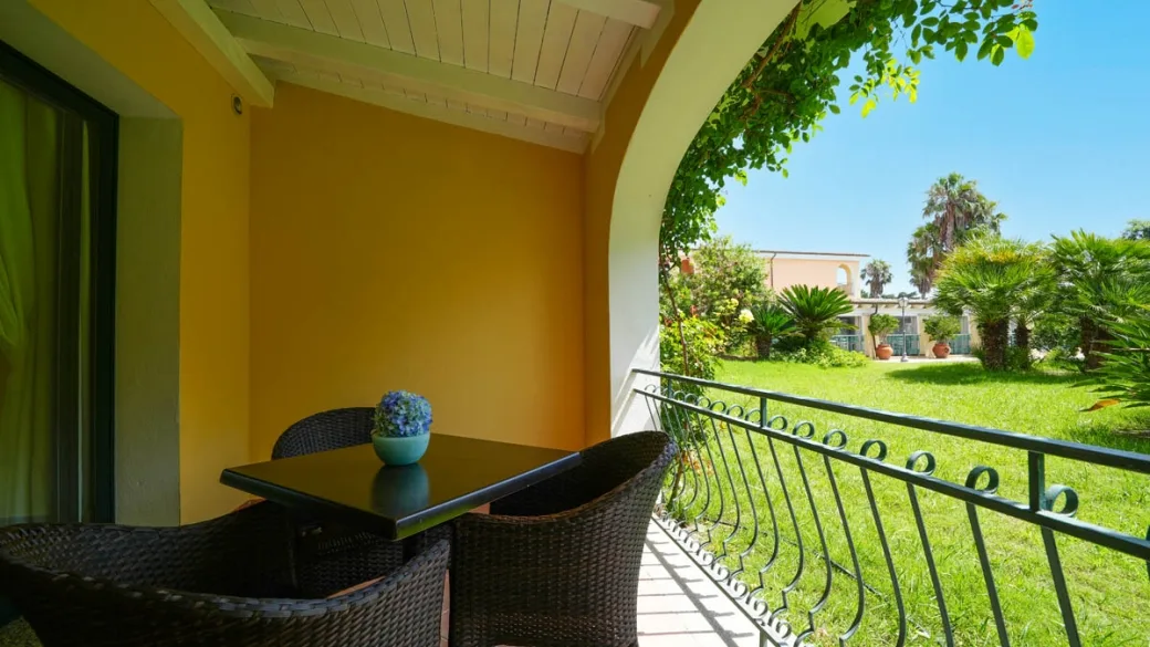 Balcone con tavolino e poltrone vista giardino del resort