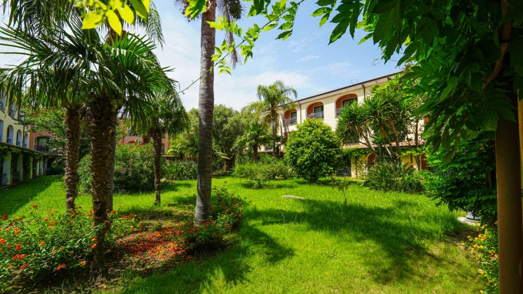 Giardino rigoglioso con palme e prato tra gli edifici del resort