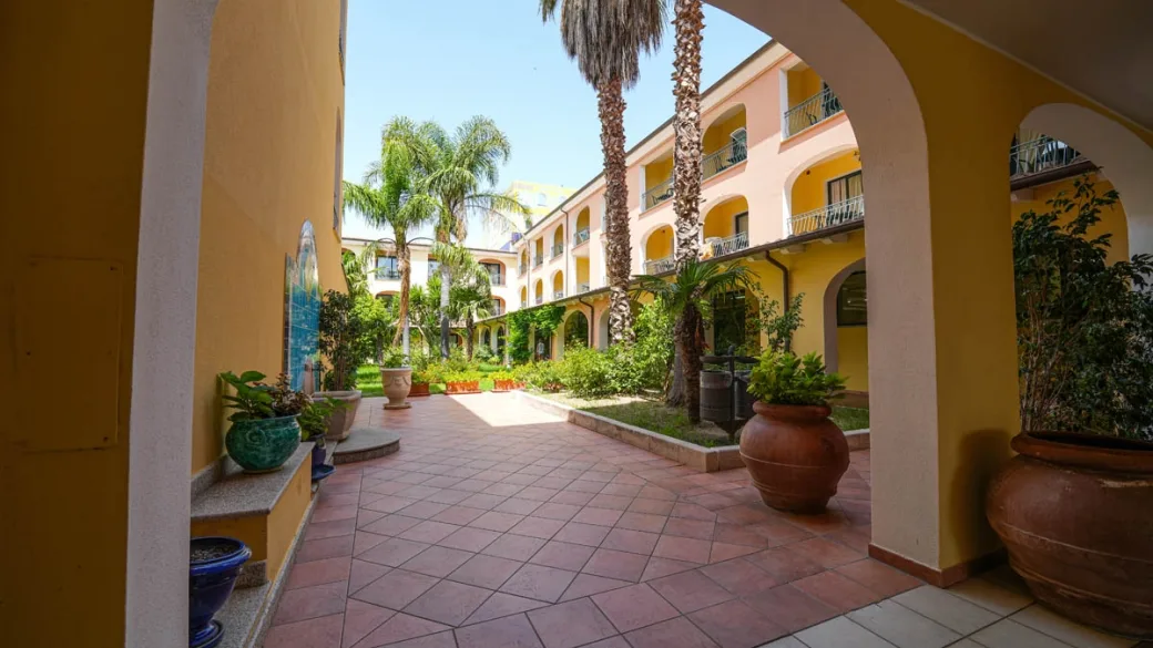 Cortile interno con palme, archi e piante in vaso
