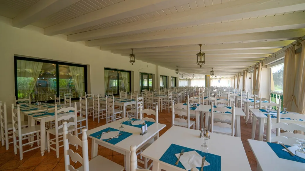 Sala ristorante con tavoli apparecchiati e tovagliette azzurre