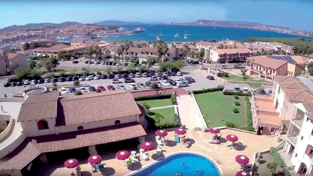 Vista panoramica aerea del villaggio con piscina, ombrelloni e mare sullo sfondo