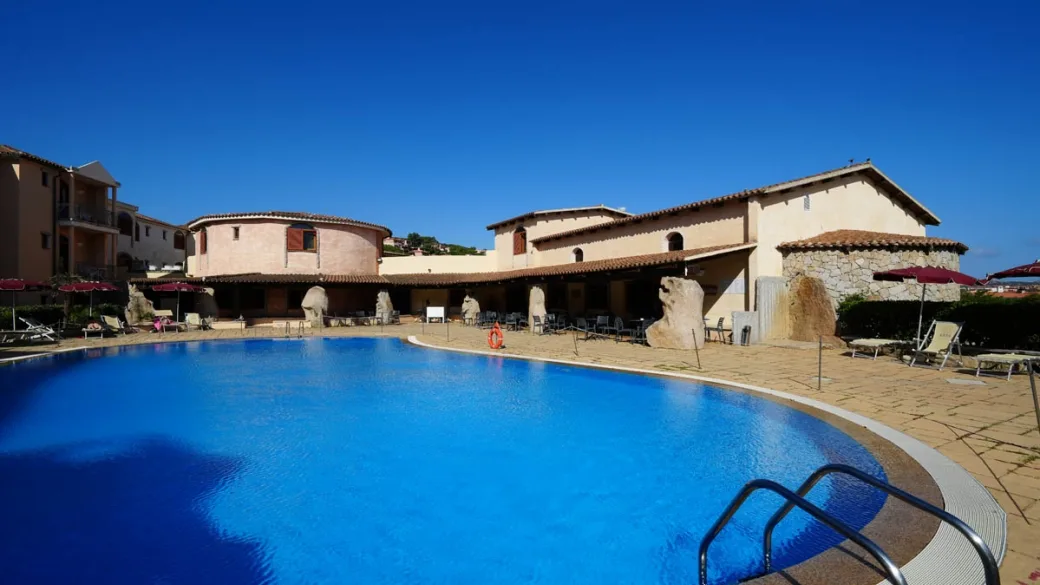 Piscina con vista sull'edificio in pietra e terrazza con tavolini