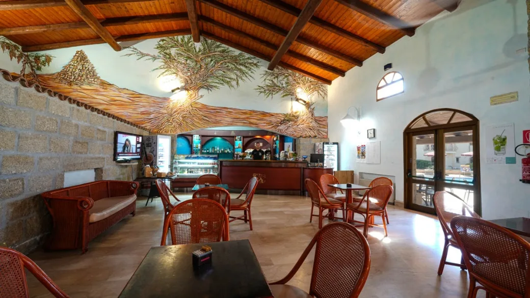 Bar interno con soffitto in legno, decorazioni murali e arredi in rattan