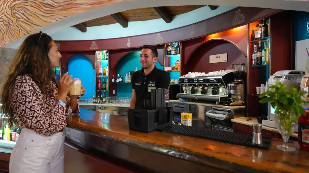 Bancone bar con barista che serve una bevanda a una cliente