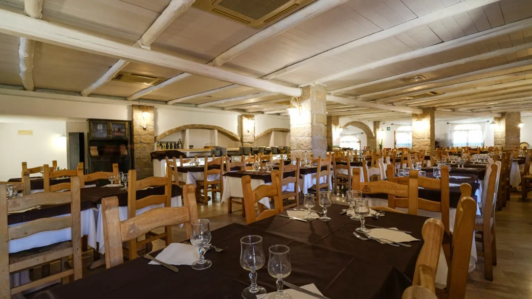 Sala ristorante rustica con tavoli, sedie in legno e archi in pietra