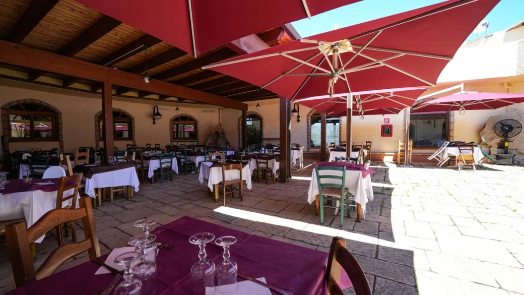 Terrazza ristorante esterna con ombrelloni rossi e tavoli apparecchiati