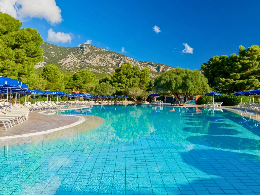 Piscina con acqua limpida circondata da pini e montagne