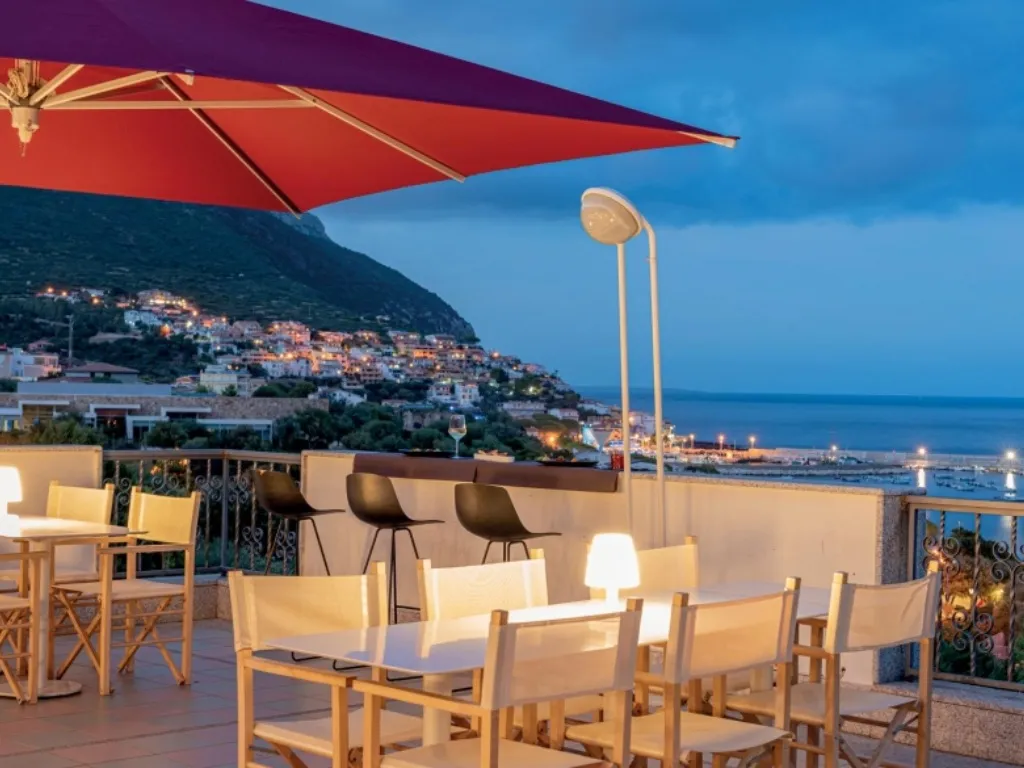 Terrazza bar con ombrellone rosso e vista sul mare al crepuscolo