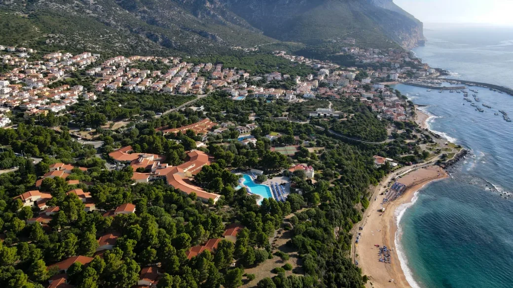 Veduta aerea del resort tra montagne e costa al tramonto