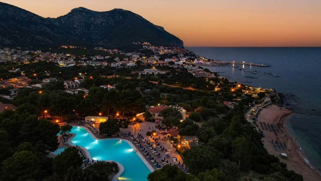 Resort illuminato di notte con piscina turchese vista mare