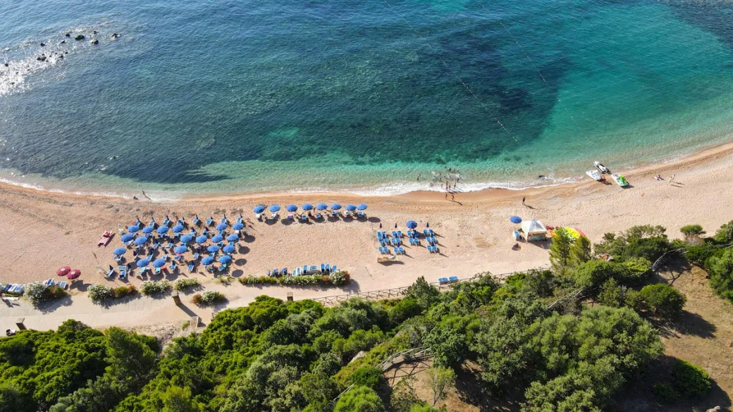 Spiaggia con ombrelloni blu e mare cristallino dall'alto
