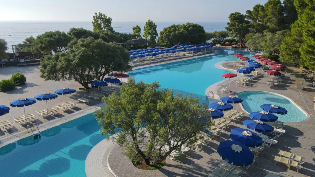 Piscina con ombrelloni blu e rossi vista mare