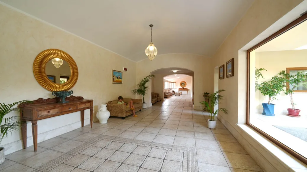 Hall interna luminosa con specchio dorato e piante