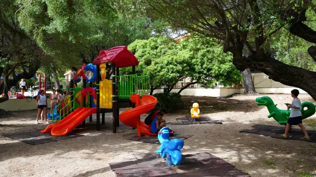 Area giochi per bambini con scivoli colorati all'ombra degli alberi