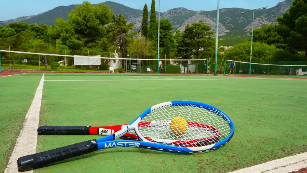 Campo da tennis con racchette e palline tra le montagne