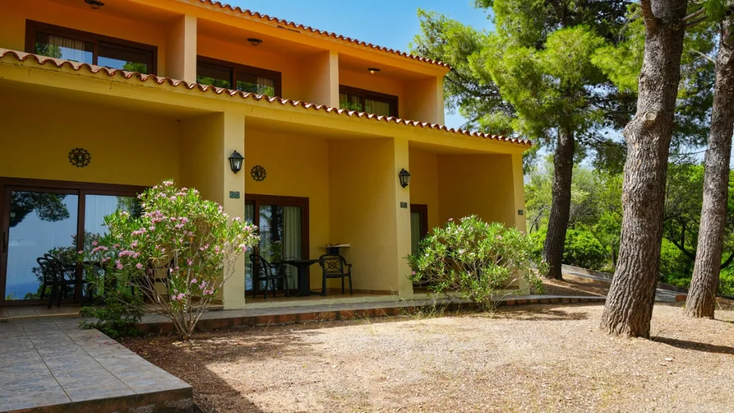 Veranda con tavolino e vista sulla piscina con ombrelloni rossi