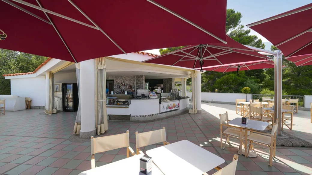 Terrazza bar con ombrelloni rossi e bancone