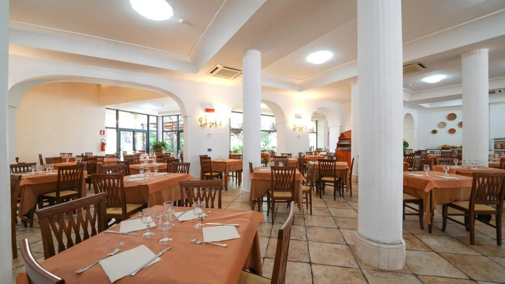 Sala ristorante interna con tavoli apparecchiati e colonne bianche
